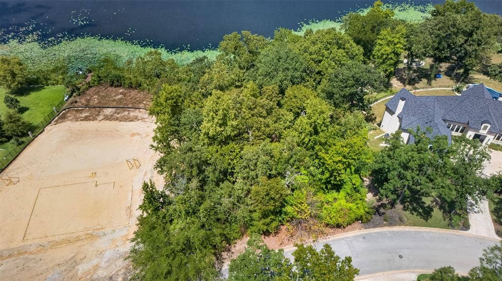 4513 Cascades Shoreline Drive, Tyler, TX 75709 Expansive land parcel featuring mature trees, a sand court, and a paved street frontage