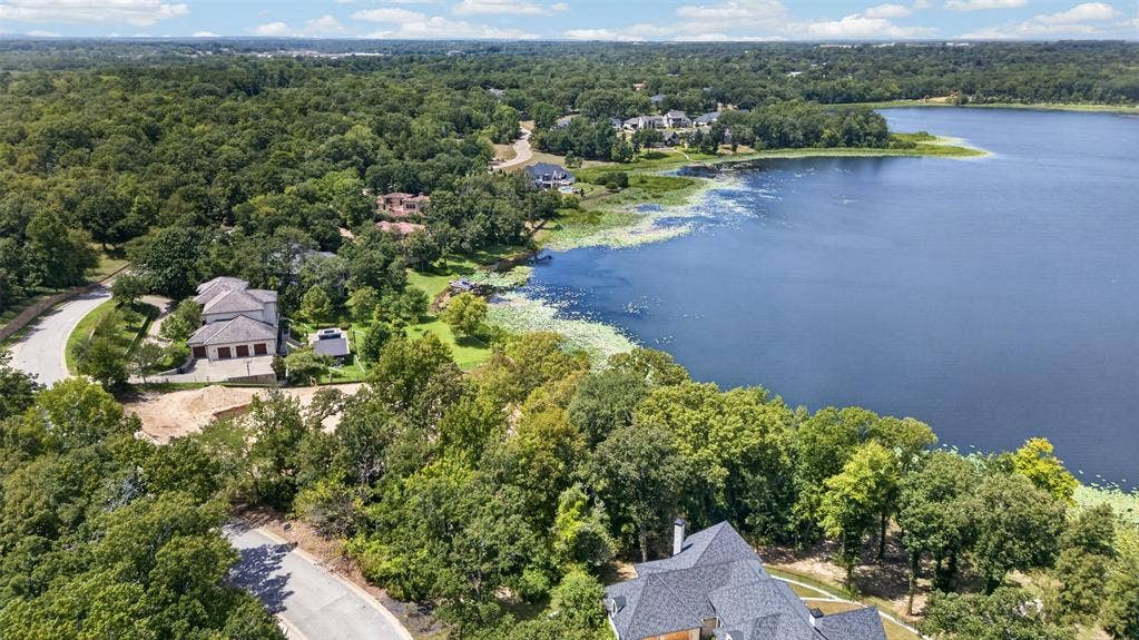 4513 Cascades Shoreline Drive, Tyler, TX 75709 Expansive lakefront property featuring mature tree coverage, a curved paved driveway, and a multi-car garage