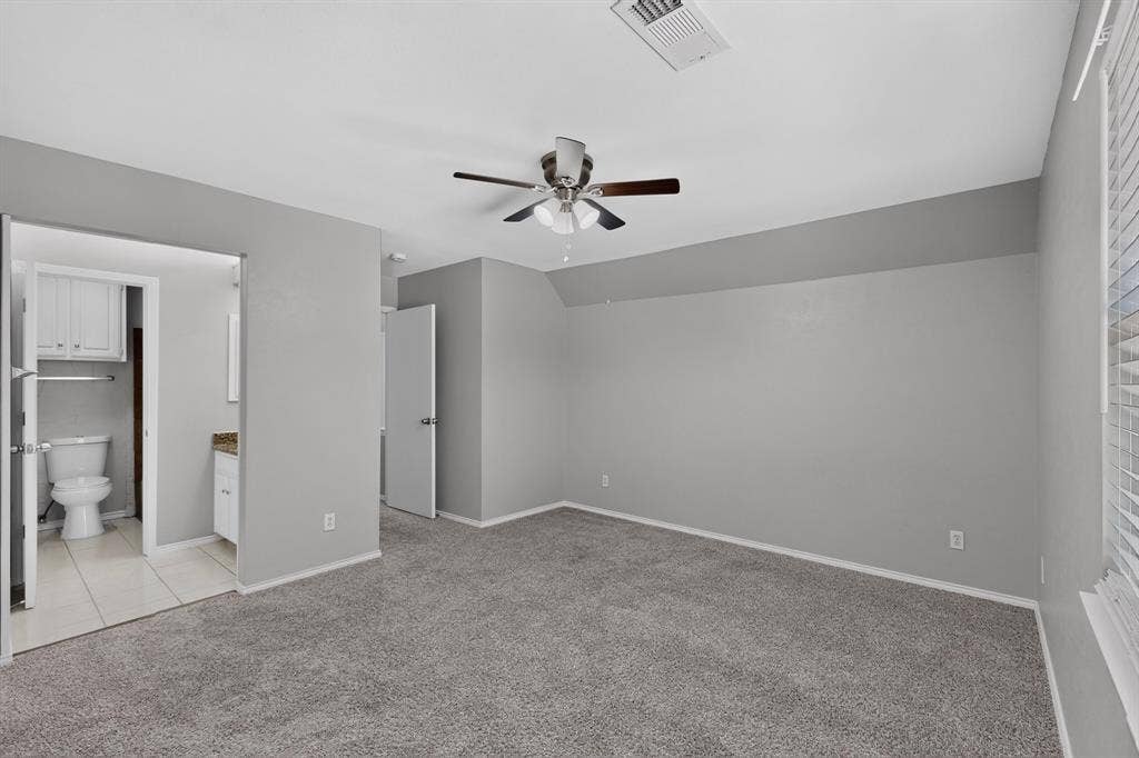 Spacious room featuring carpeting, ceiling fan, and window with blinds