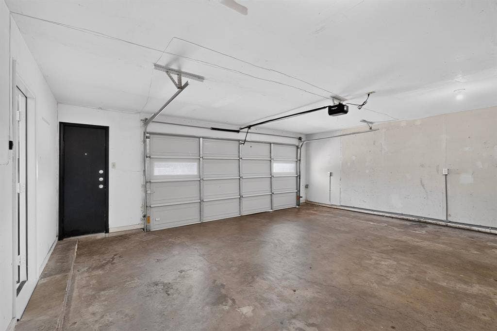Attached garage with a concrete floor, an overhead garage door, and a black entry door