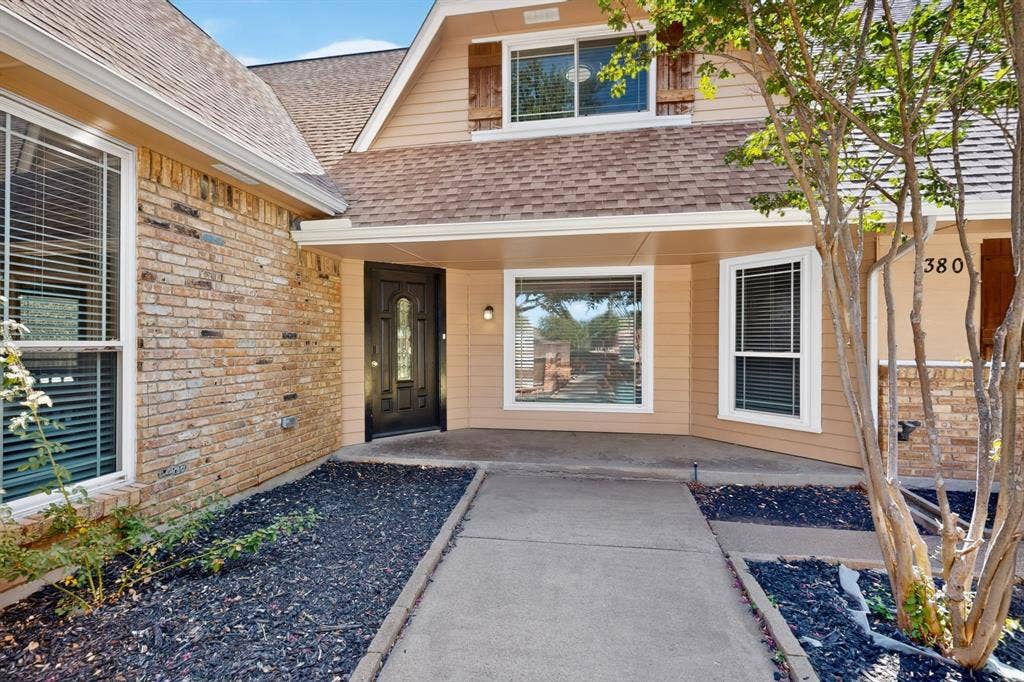 Brick and siding exterior with a concrete walkway, covered entryway, and integrated landscaping