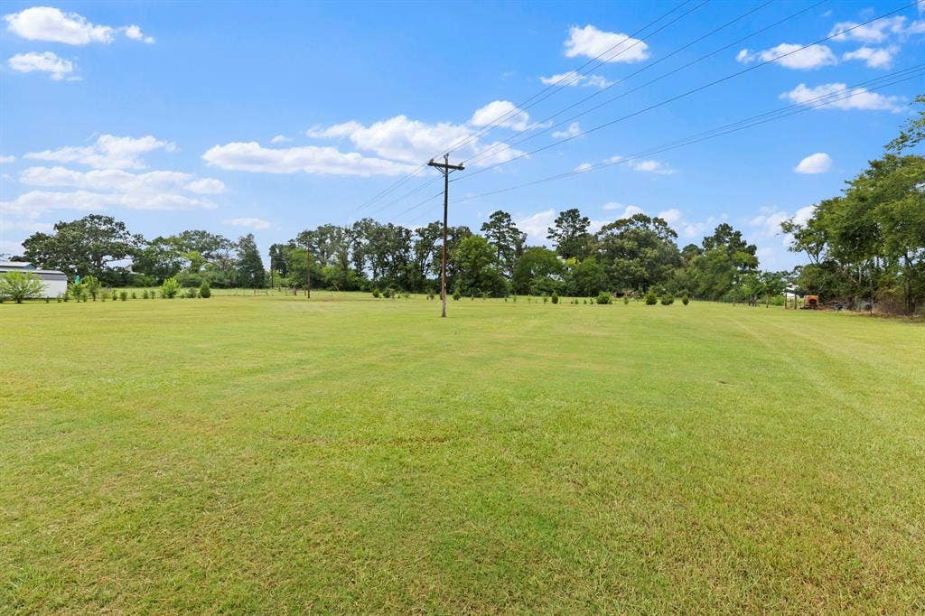 22477 County Road 2166, Troup, TX 75789 Expansive grass field with partial fencing and distant trees