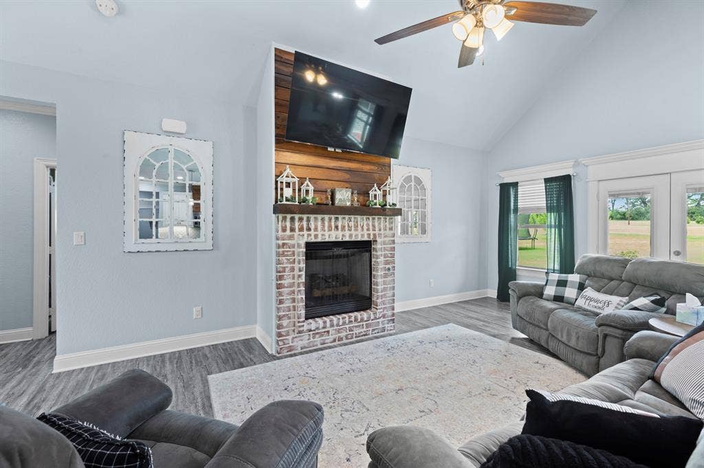22477 County Road 2166, Troup, TX 75789 Vaulted ceiling, wood-finish flooring, brick fireplace with wood mantel, built-in ceiling fan, and French doors