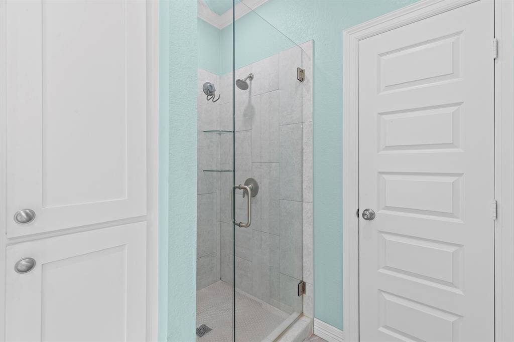 22477 County Road 2166, Troup, TX 75789 Frameless glass shower enclosure with a tiled interior, recessed shelving, and a rain shower head