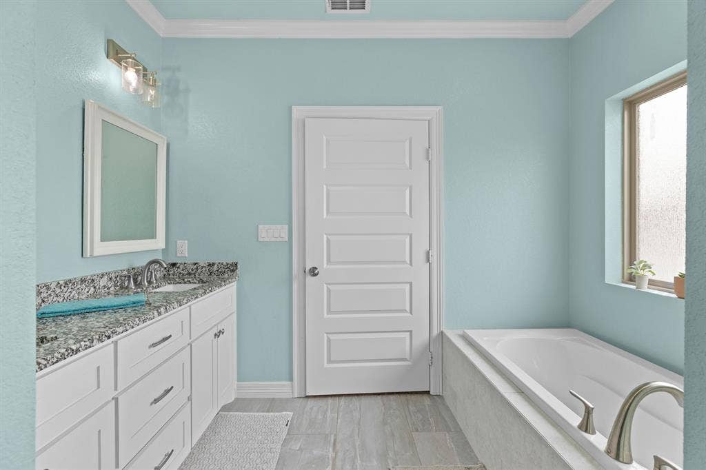 22477 County Road 2166, Troup, TX 75789 Bathroom featuring a single vanity with stone countertop, undermount sink, white cabinetry, and a built-in bathtub