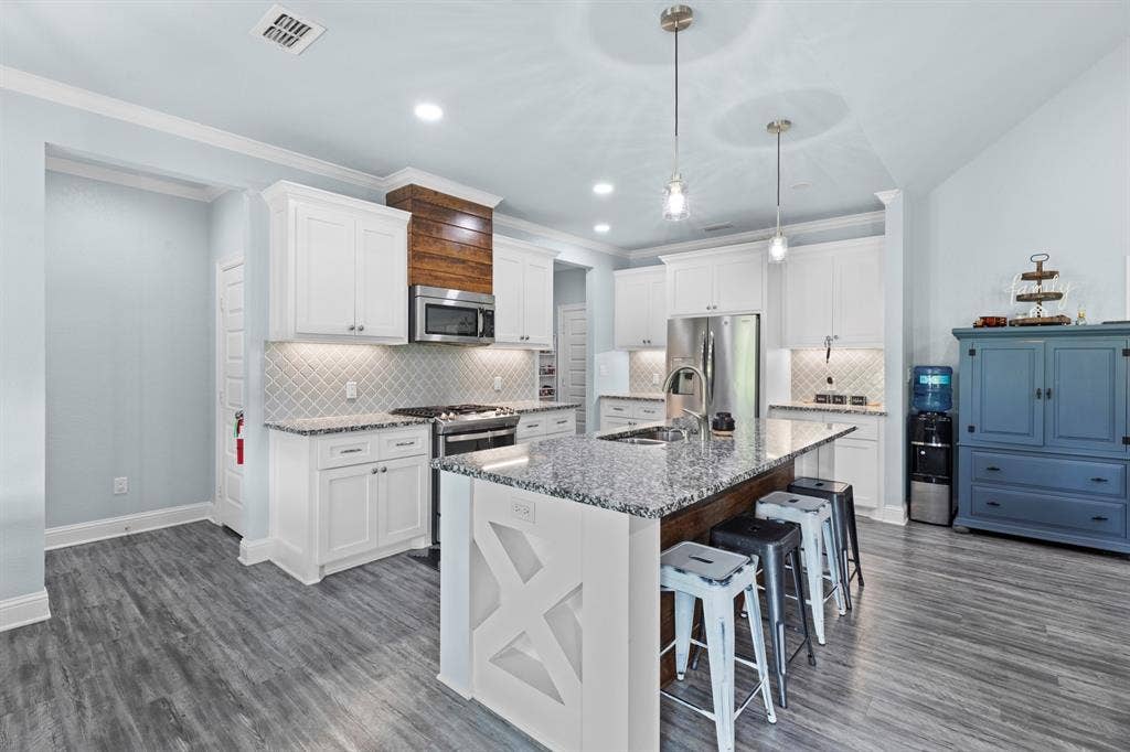 22477 County Road 2166, Troup, TX 75789 Kitchen featuring white cabinetry, gray wood-finish flooring, a central island with a granite countertop, stainless steel appliances, and pendant lighting