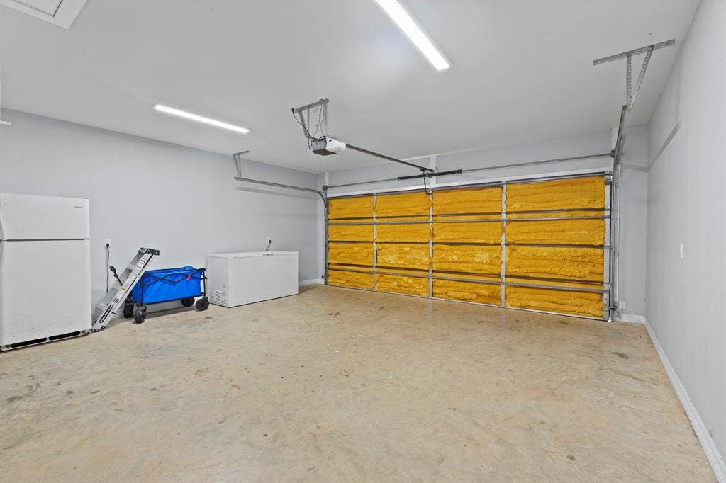 22477 County Road 2166, Troup, TX 75789 Spacious garage with concrete flooring, light gray wall paint, and overhead lighting