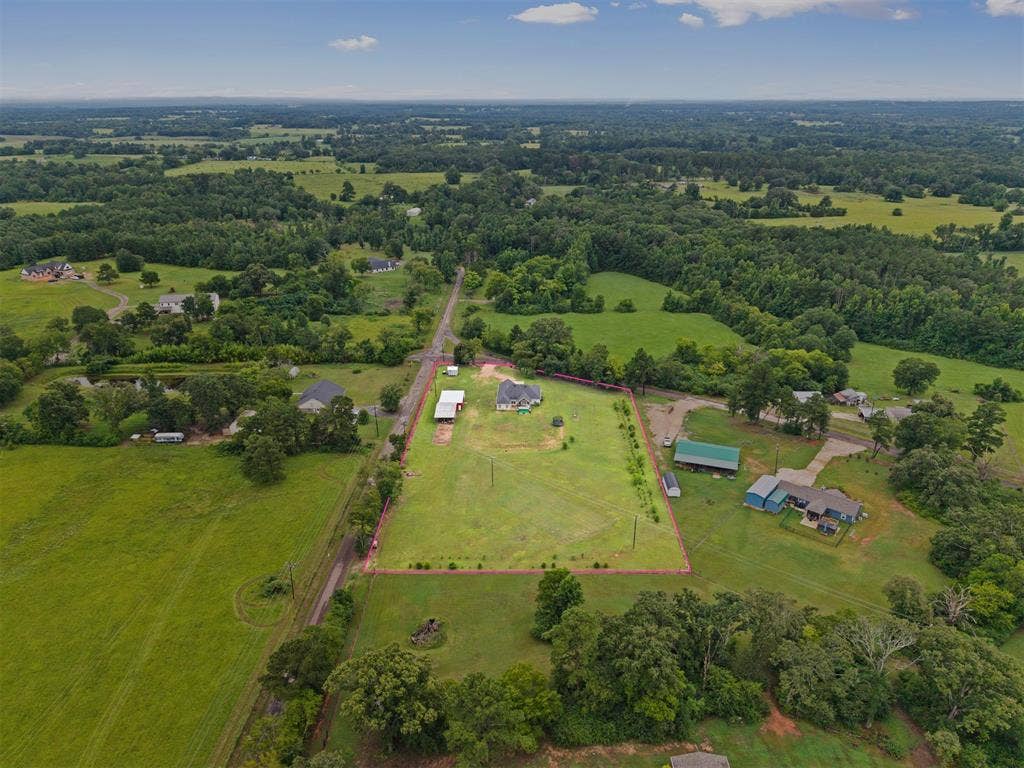 22477 County Road 2166, Troup, TX 75789 Expansive rural property featuring a main residence, multiple outbuildings, and mature trees