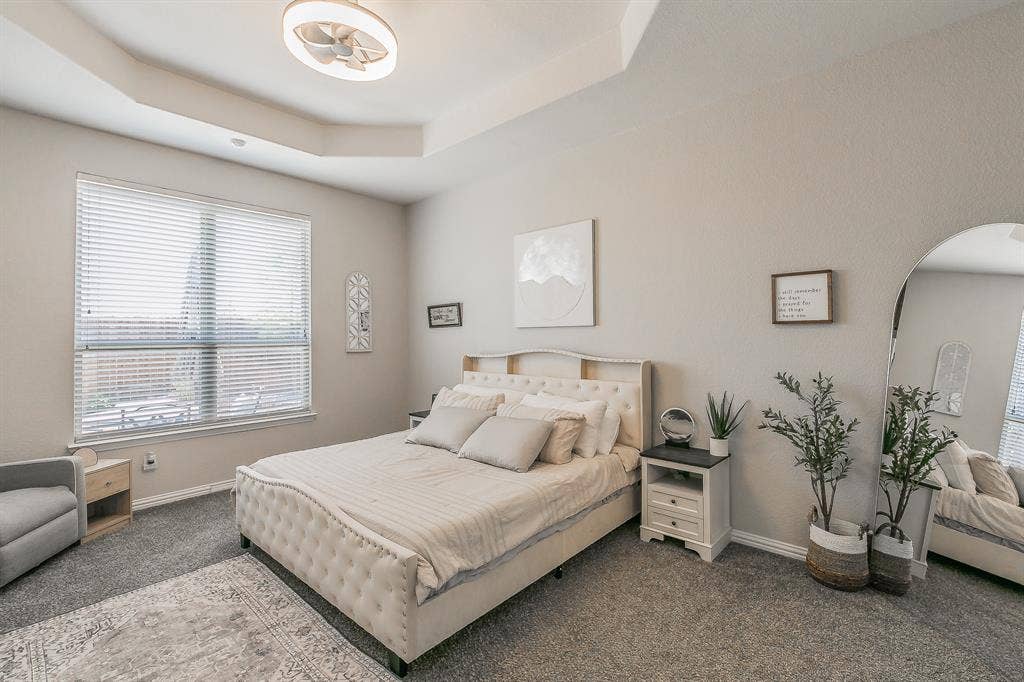 3020 Bella Lago Drive, Fort Worth, TX 76177 Tray ceiling with a modern ceiling fan, large window with horizontal blinds, and neutral wall tones