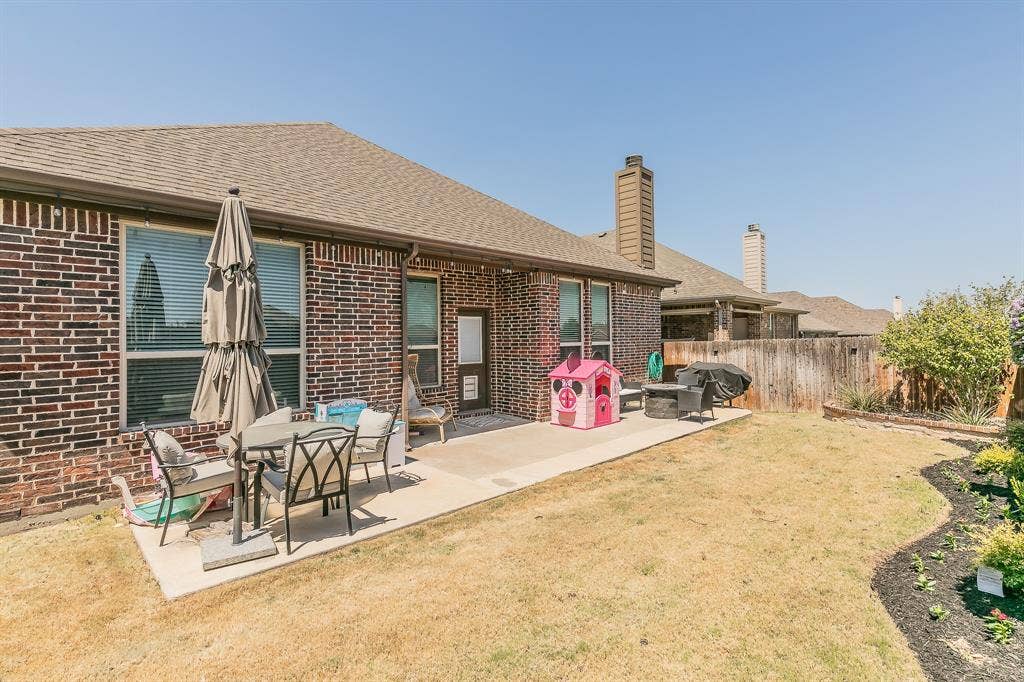 3020 Bella Lago Drive, Fort Worth, TX 76177 Brick exterior with a concrete patio, wood fence, and landscaped garden bed