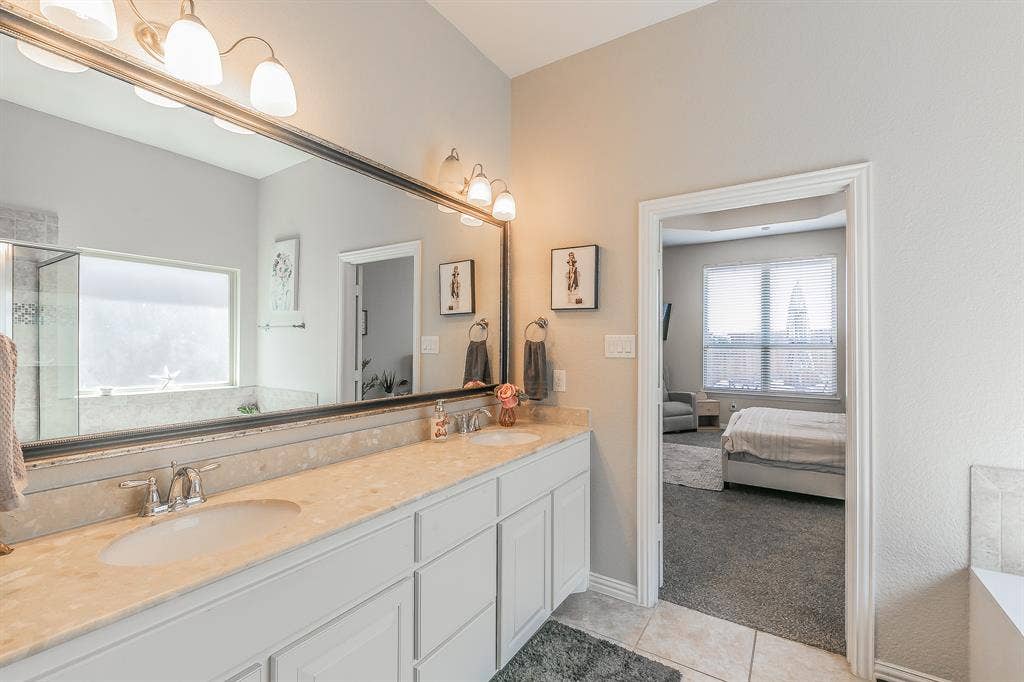 3020 Bella Lago Drive, Fort Worth, TX 76177 Dual sink vanity with light-toned countertop, large wall-mounted mirror, and tile flooring