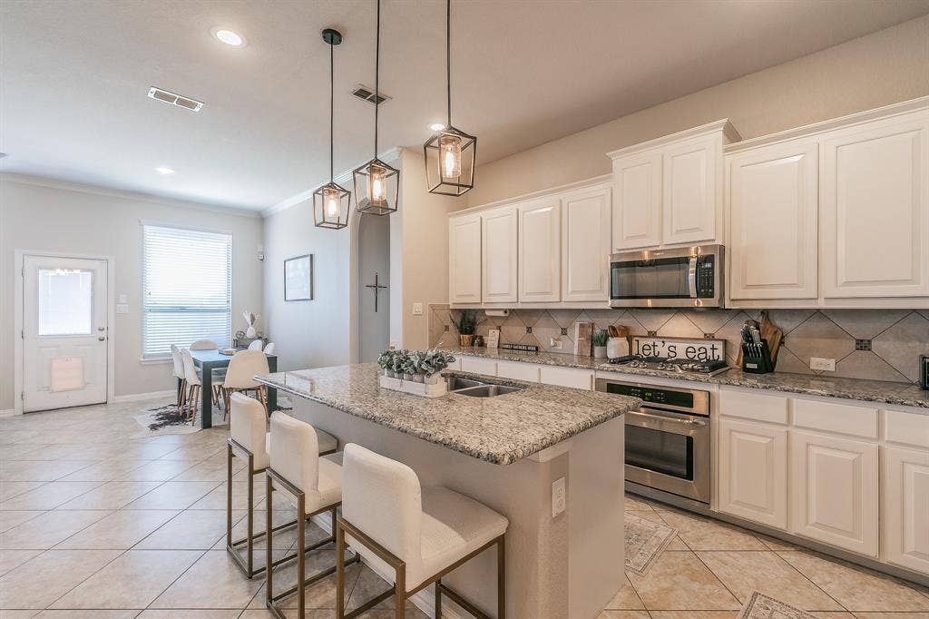 3020 Bella Lago Drive, Fort Worth, TX 76177 Kitchen island with granite countertop, new lighting, stainless steel appliances, white cabinetry, decorative tile backsplash, and recessed lighting