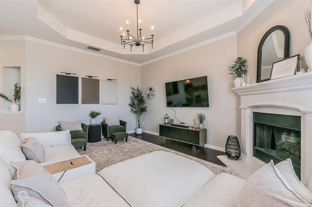 3020 Bella Lago Drive, Fort Worth, TX 76177 Tray ceiling with crown molding, dark wood-finish flooring, recessed wall niche, fireplace with mantel, and a black chandelier