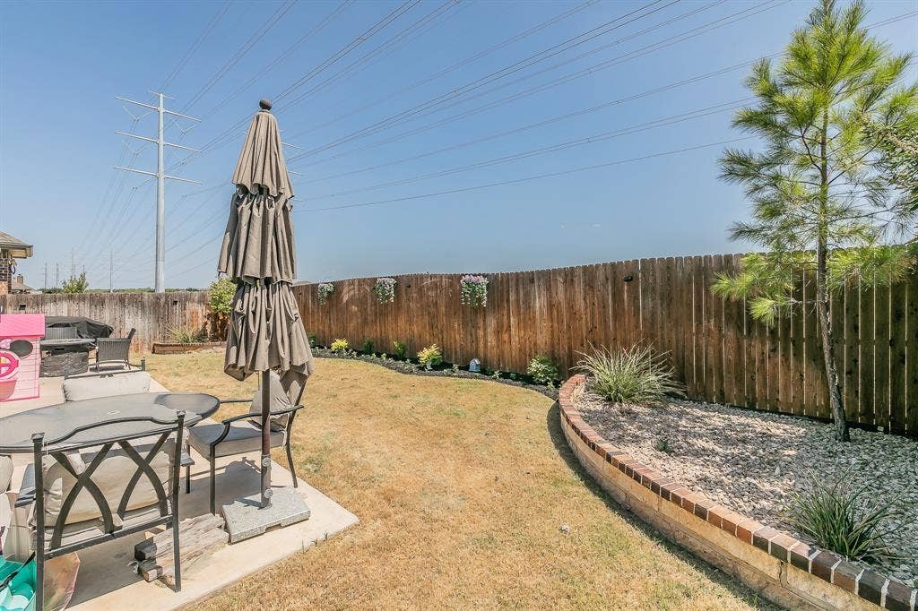 3020 Bella Lago Drive, Fort Worth, TX 76177 Expansive backyard featuring a wood privacy fence, concrete patio, and a curved brick-edged planter