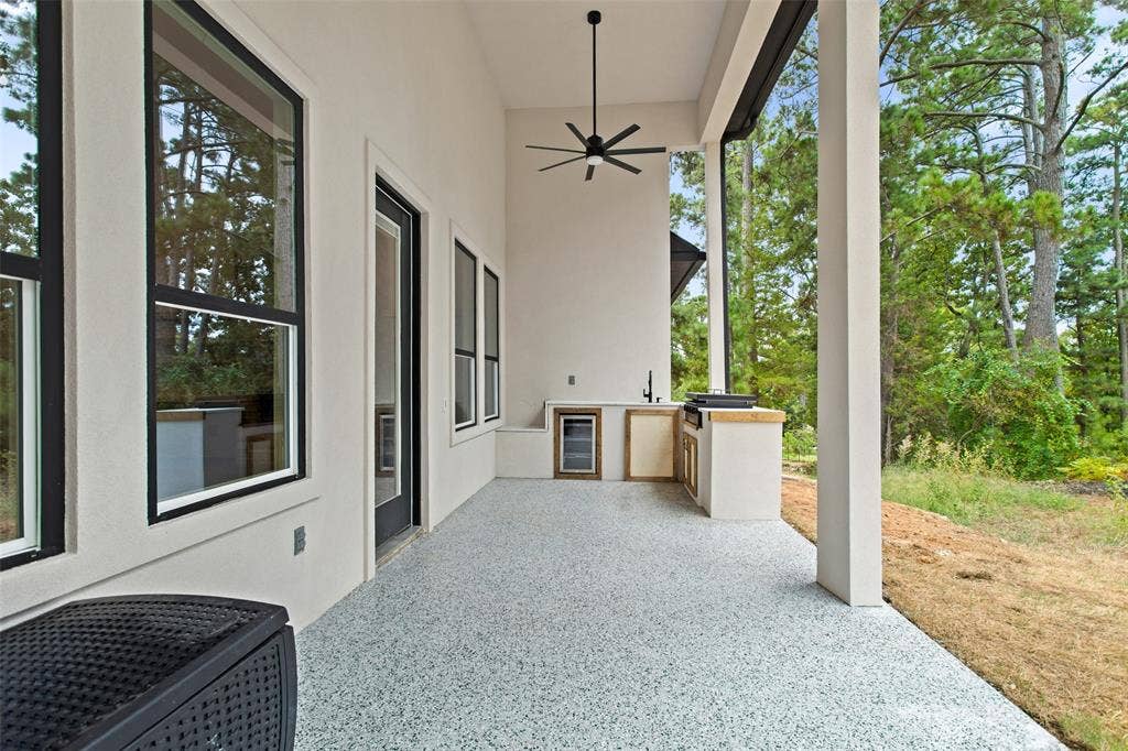 Spacious covered patio with a built-in outdoor kitchen, recessed lighting, and a ceiling fan