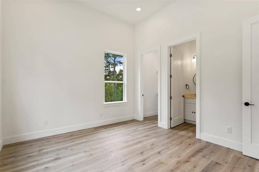 Recessed lighting, wood-finish flooring, white walls, white trim, and a white vanity with a wooden countertop