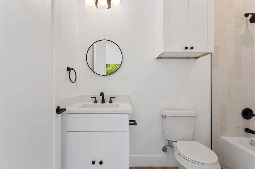 White vanity with an integrated sink and matte black faucet, illuminated by an overhead light fixture