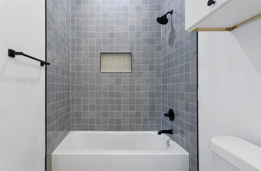 Integrated bathtub with tiled surround featuring a recessed niche