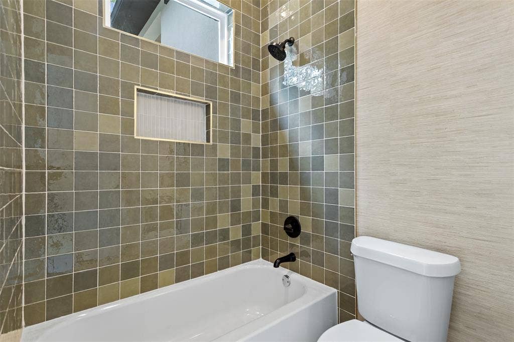 Subway tile tub surround with integrated shower niche, black finish shower fixtures, and a white porcelain tub