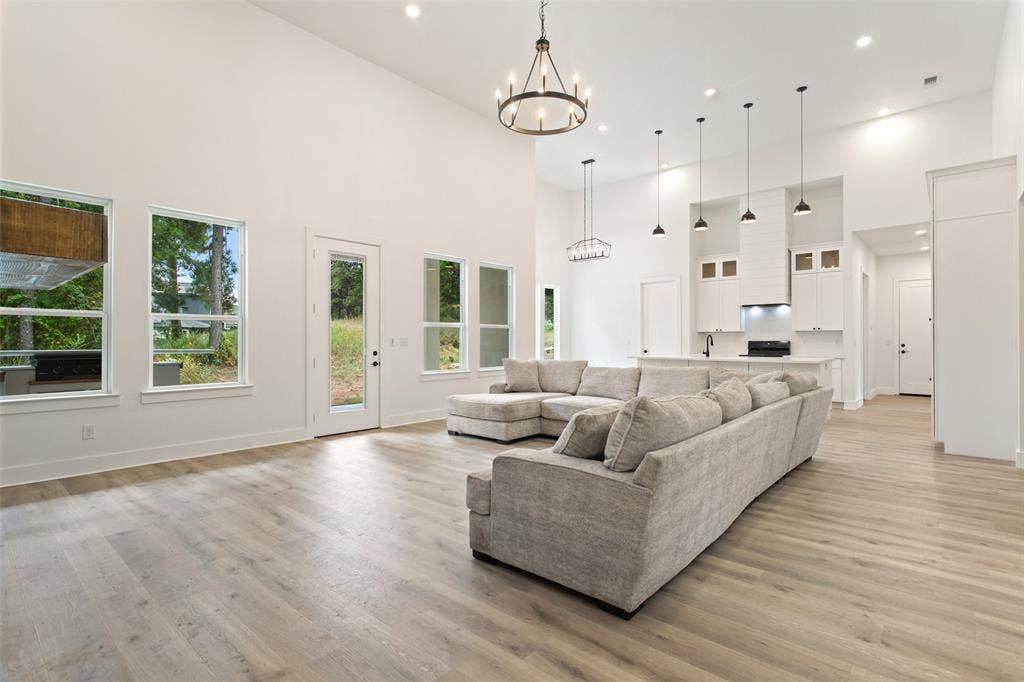 Soaring vaulted ceilings with recessed lighting, wood-finish flooring, and a modern kitchen featuring an island with pendant lighting and white cabinetry