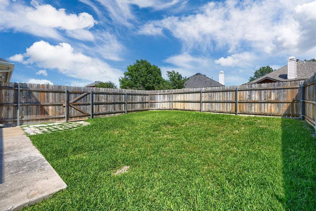 Grassed backyard featuring a wood fence perimeter and a concrete patio