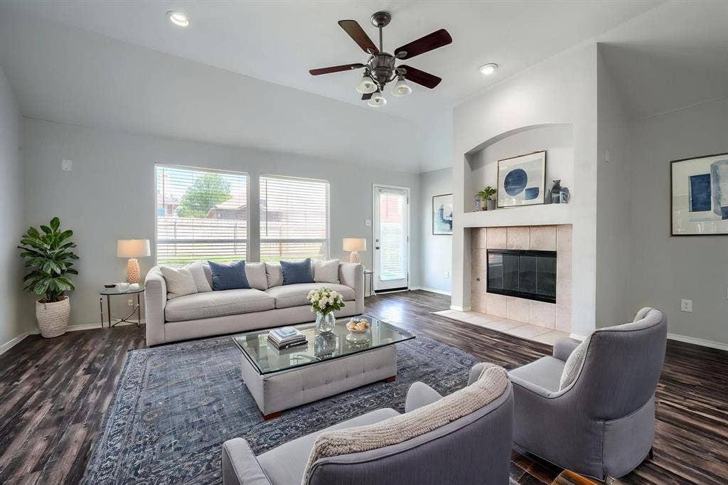 Vaulted ceiling with a ceiling fan, recessed lighting, wood-finish flooring, and a fireplace with a tile surround and hearth