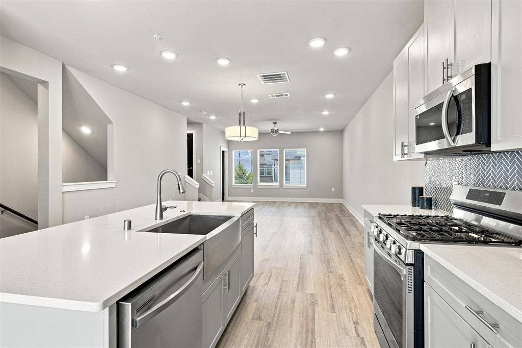 3352 Norris Street, Plano, TX 75074 Kitchen island with undermount sink, stainless steel appliances, and white cabinetry