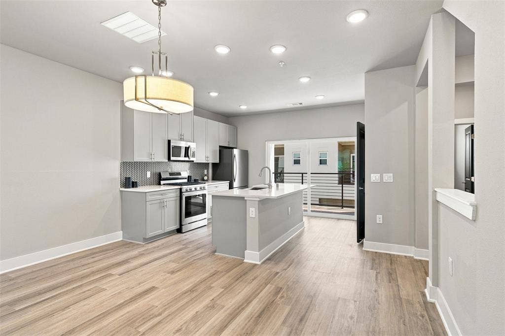 3352 Norris Street, Plano, TX 75074 Open-concept kitchen with wood-finish flooring, recessed lighting, and a modern island featuring a gooseneck faucet