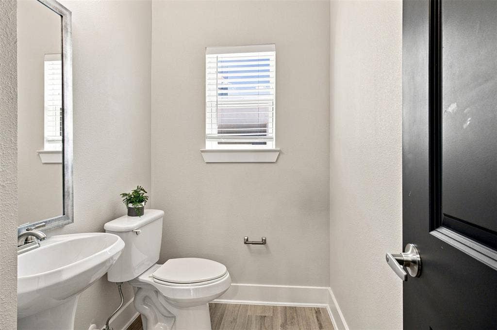 3352 Norris Street, Plano, TX 75074 Pedestal sink with a framed mirror, window with blinds, wood-finish flooring, and a towel bar