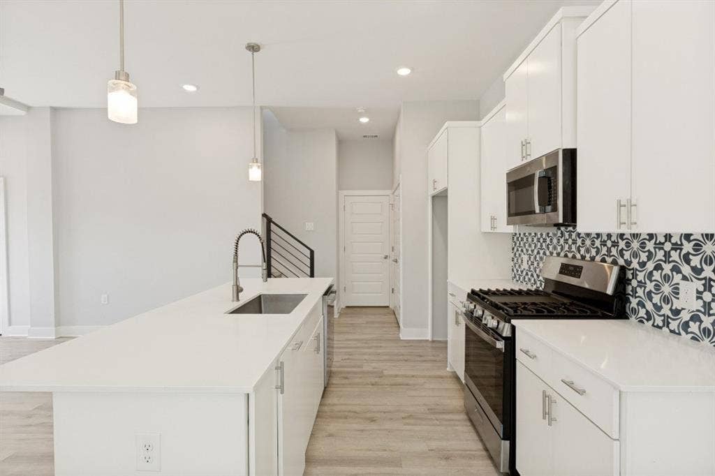 1042 Rosemont Street, #1, Austin, TX 78723 Bright kitchen featuring a center island, stainless steel appliances, white cabinetry, and a patterned tile backsplash