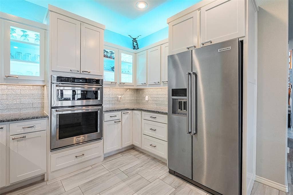 109 Briarwood Drive, Gun Barrel City, TX 75156 White cabinetry, stainless steel microwave and oven, stainless steel refrigerator, granite countertops, and light-toned tile flooring