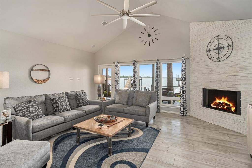 109 Briarwood Drive, Gun Barrel City, TX 75156 Vaulted ceiling with an installed ceiling fan, floor-to-ceiling windows, modern fireplace with a stacked stone surround, and Tile flooring