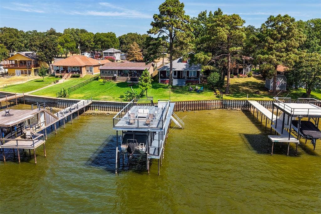109 Briarwood Drive, Gun Barrel City, TX 75156 Waterfront property featuring a private boat dock with an upper-level deck, a second boat dock with a covered slip, and a manicured grassy lawn