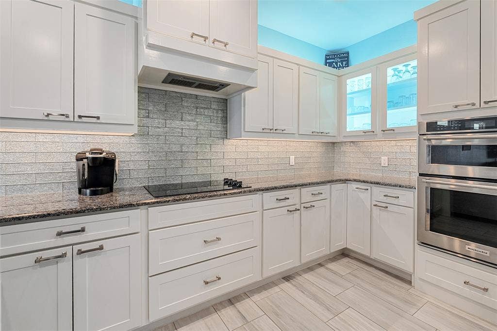 109 Briarwood Drive, Gun Barrel City, TX 75156 White shaker cabinetry, dark speckled countertops, tile backsplash, built-in stainless steel double ovens, and tile flooring