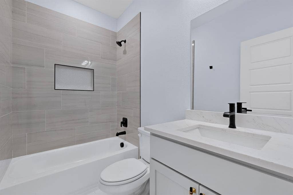 102 Redondo Drive, Gun Barrel City, TX 75156 Bathtub with light-toned tiled surround, integrated shower niche, and matte black fixtures