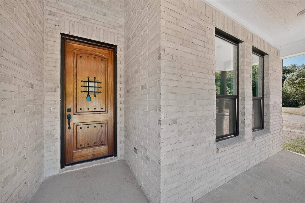 102 Redondo Drive, Gun Barrel City, TX 75156 Whitewashed brick exterior with a wood-panel entry door featuring decorative metalwork