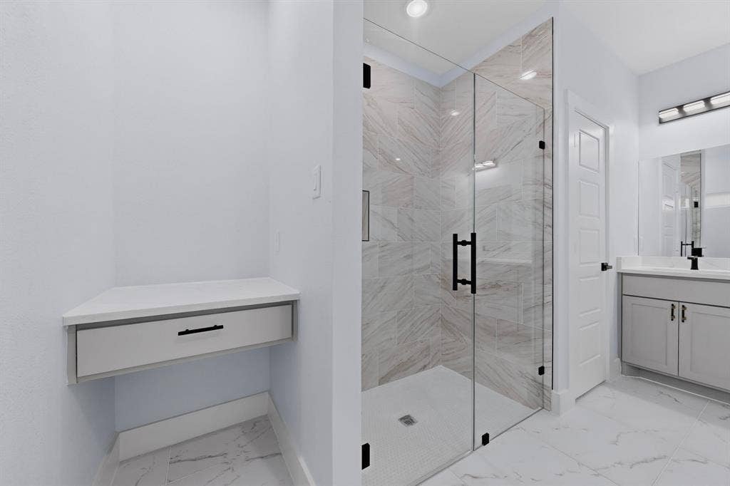 102 Redondo Drive, Gun Barrel City, TX 75156 Corner vanity with drawer, glass-enclosed shower with tile surround, single vanity with under-sink storage, and large format floor tiling