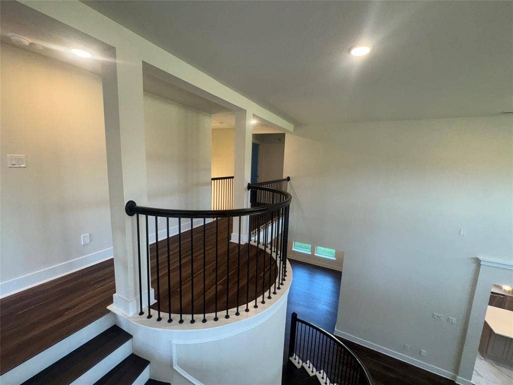 1701 Shamrock Green, Mesquite, TX 75181 Curved staircase with black wrought iron balusters, wood-finish flooring, recessed lighting, and a neutral color palette
