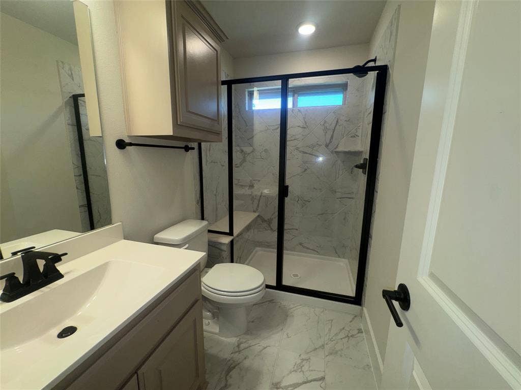 1701 Shamrock Green, Mesquite, TX 75181 Walk-in shower with black-framed glass enclosure, integrated bench, and marble-patterned tile surround