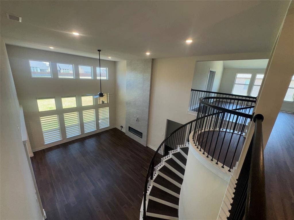 1701 Shamrock Green, Mesquite, TX 75181 Two-story ceiling, large windows with horizontal blinds, built-in fireplace, dark wood-finish flooring, and a spiral staircase with metal balusters