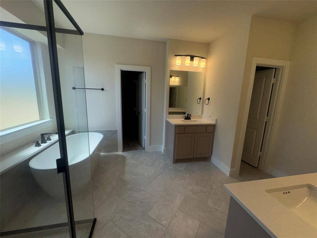 1701 Shamrock Green, Mesquite, TX 75181 Freestanding soaking tub with matte black fixtures, glass-enclosed shower, dual vanity, and tiled flooring