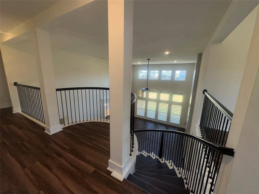 1701 Shamrock Green, Mesquite, TX 75181 Open concept interior with wood-finish flooring, two-story windows with plantation shutters, a curved staircase with black metal balusters, and recessed lighting