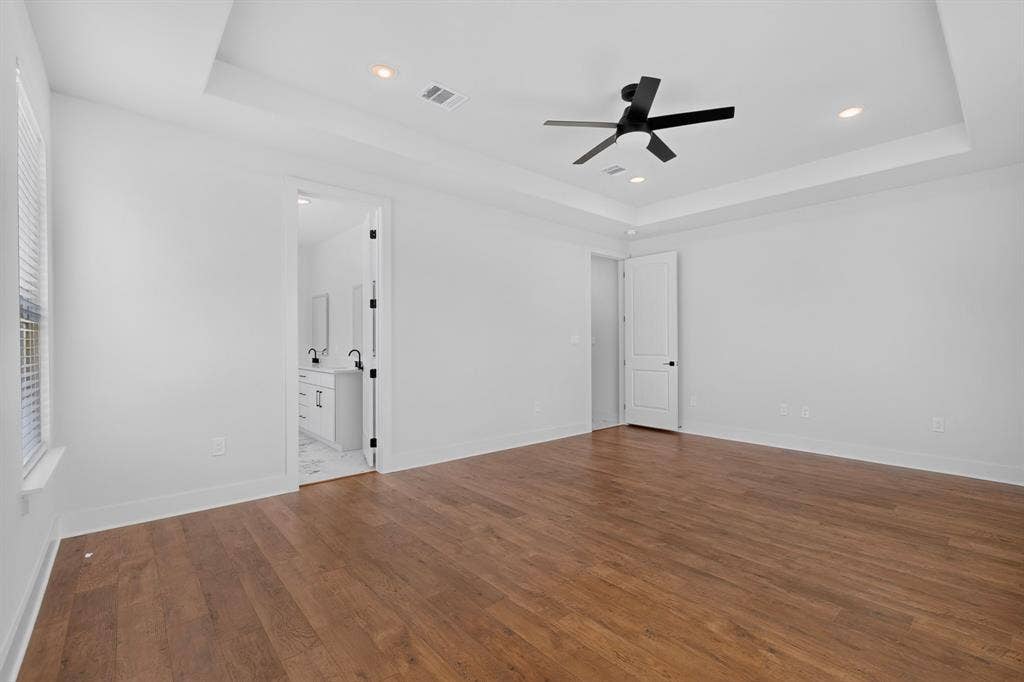 1672 Brookview Drive, Lancaster, TX 75146 Wood-finish flooring throughout, tray ceiling with recessed lighting, and a matte black ceiling fan