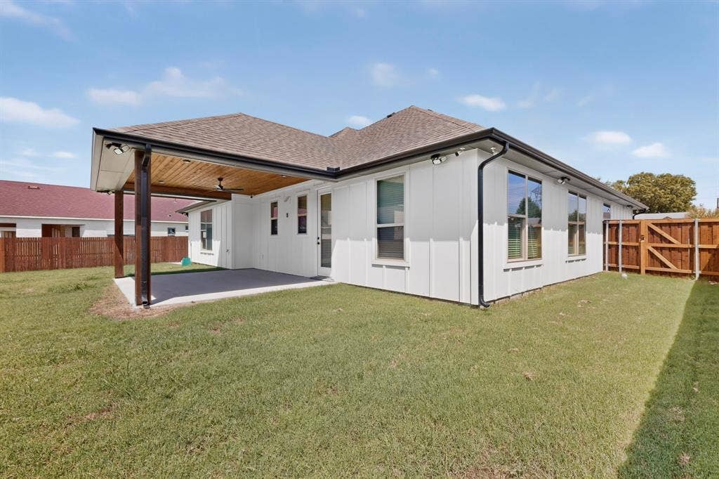 1672 Brookview Drive, Lancaster, TX 75146 White board-and-batten exterior with dark trim and a covered patio featuring a wood-finish ceiling