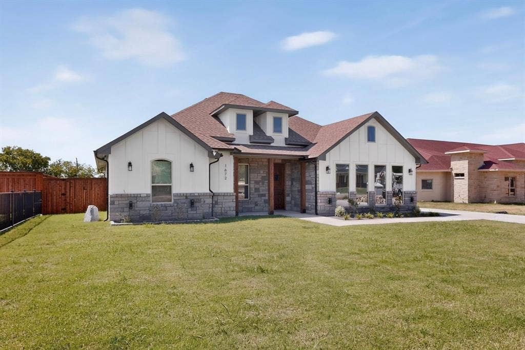 1672 Brookview Drive, Lancaster, TX 75146 exterior featuring stone and board-and-batten siding, a gable roof, and multiple dormer windows