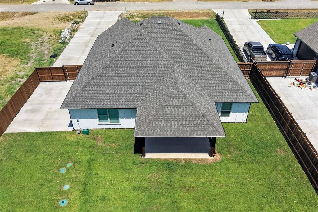 1672 Brookview Drive, Lancaster, TX 75146 Spacious property featuring a large asphalt shingle roof, light-colored siding, extensive concrete driveway, and a covered back patio