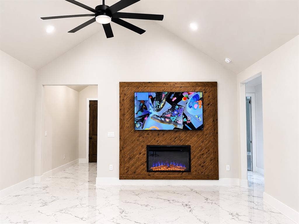 1672 Brookview Drive, Lancaster, TX 75146 Vaulted ceiling featuring a ceiling fan and recessed lighting, a wood-paneled accent wall, a built-in electric fireplace, and white-veined flooring