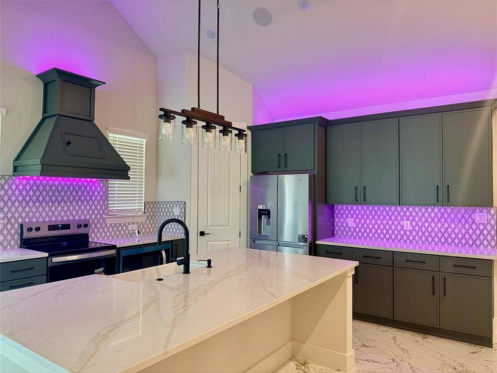 1672 Brookview Drive, Lancaster, TX 75146 Kitchen featuring a large central island with a light-toned countertop, a range hood, dark cabinetry, and a patterned tile backsplash