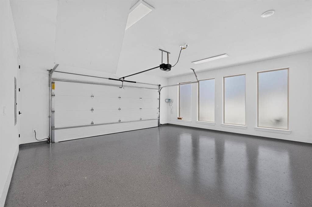 1672 Brookview Drive, Lancaster, TX 75146 Spacious garage with an automatic overhead door, four transom windows, recessed lighting, and an epoxy-coated concrete floor