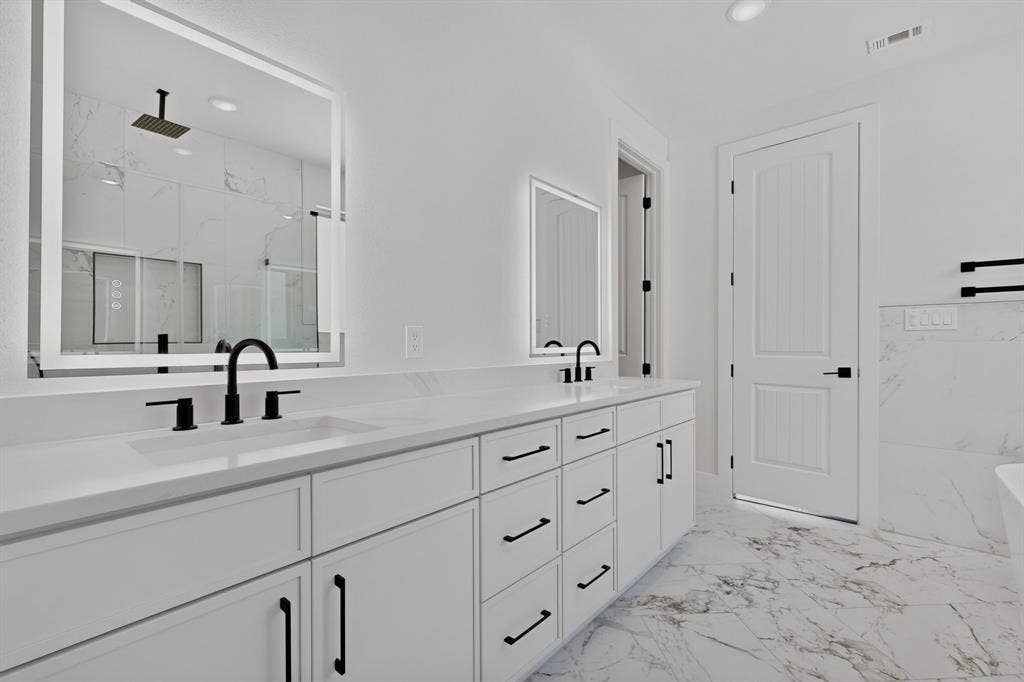 1672 Brookview Drive, Lancaster, TX 75146 Dual-sink vanity with white cabinetry, black hardware, and an illuminated mirror